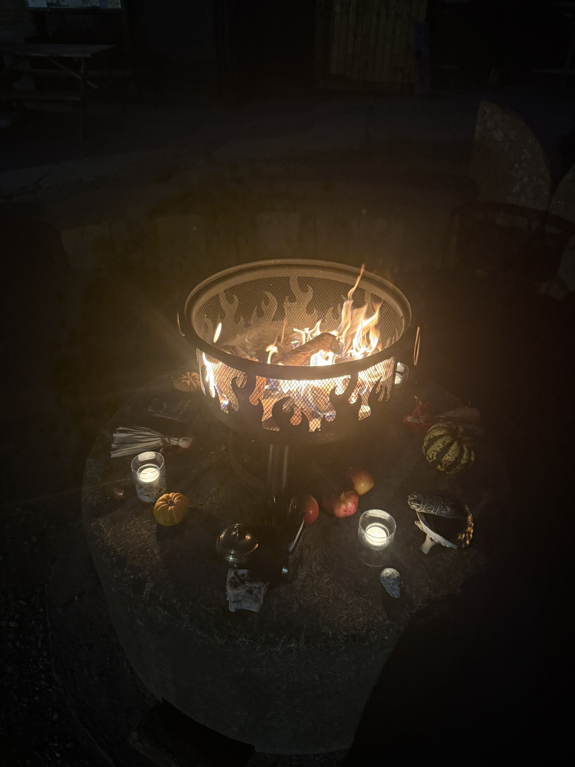 Smoke-free outdoor fire pit with decorative flame design, surrounded by pumpkins and candles, set in a cozy garden for relaxing evenings and gatherings.