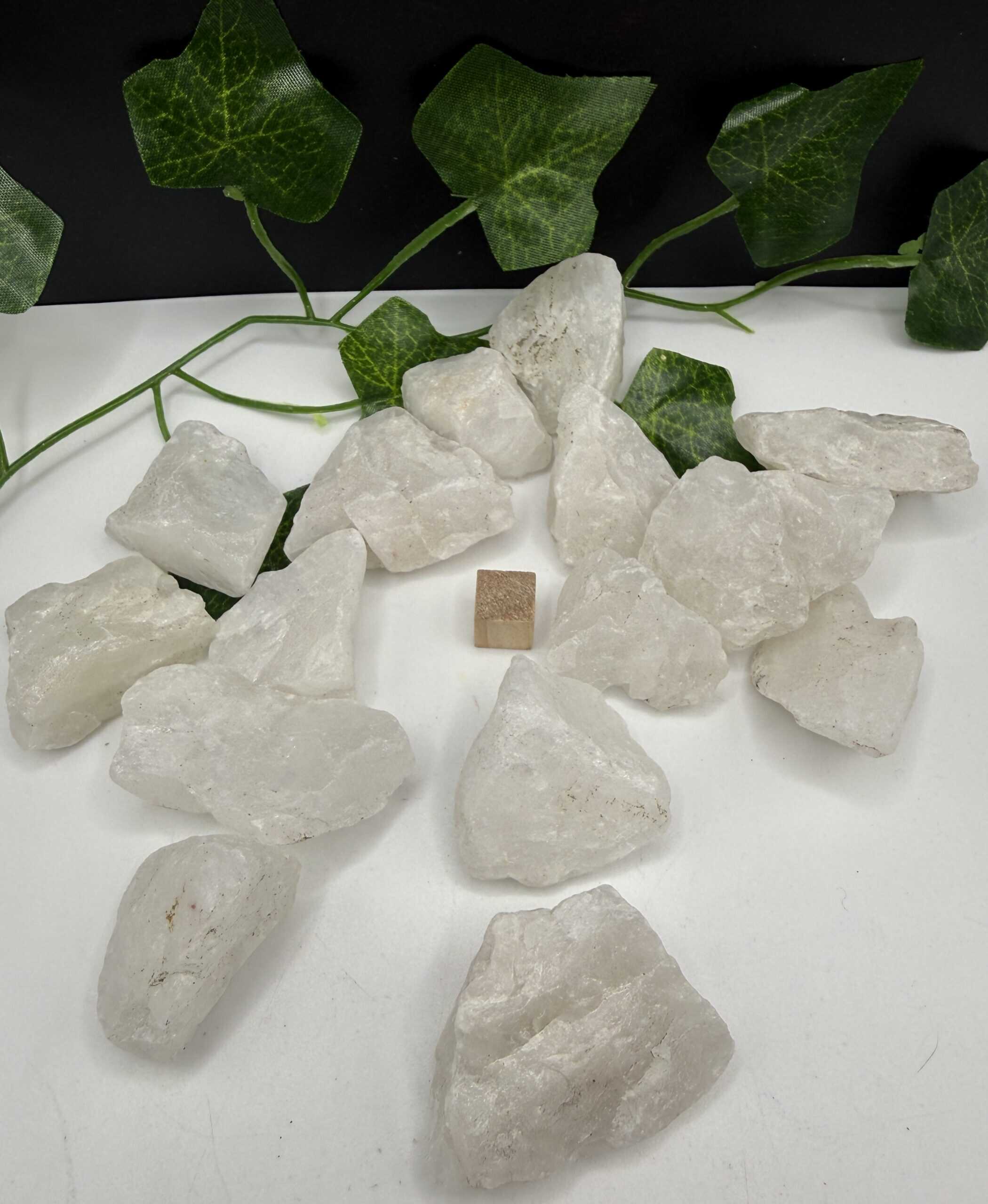 White healing crystal stones with green ivy leaves on black background, natural energy, spiritual healing, crystal therapy, holistic wellness products from The Goddess Haven.