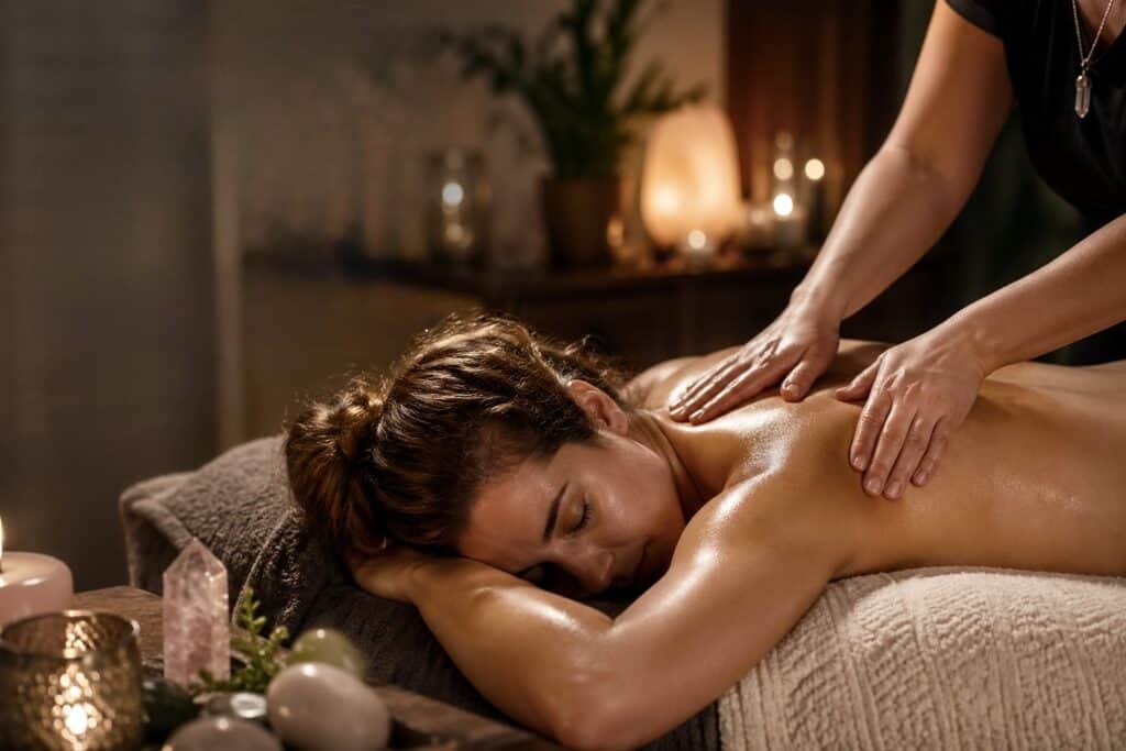 A woman receiving a soothing massage in a tranquil spa setting with warm lighting and calming decor.