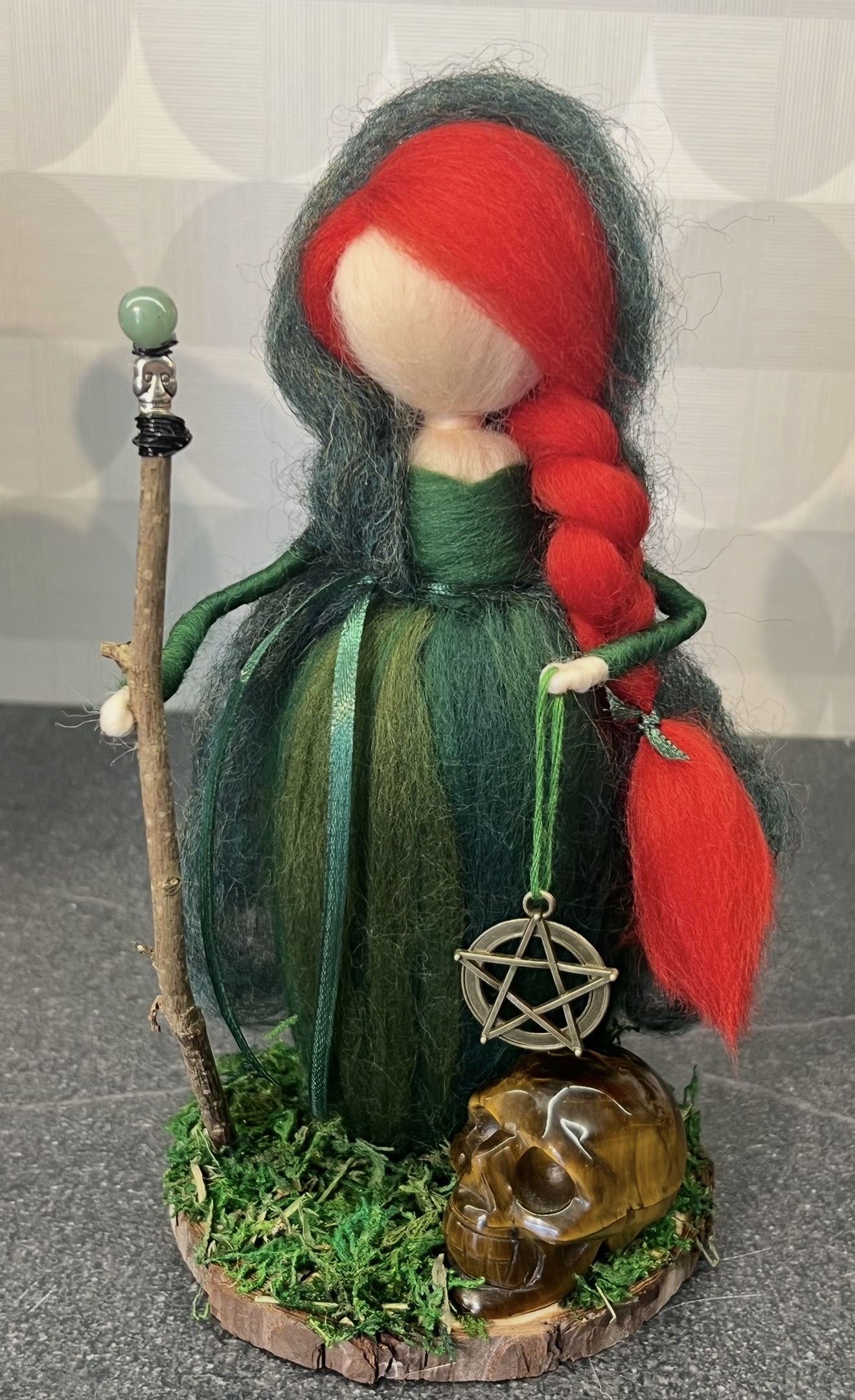Enchanting witch doll with red hair, green dress, and staff, holding a pentagram charm and skull, perfect for Halloween or mystical decor.