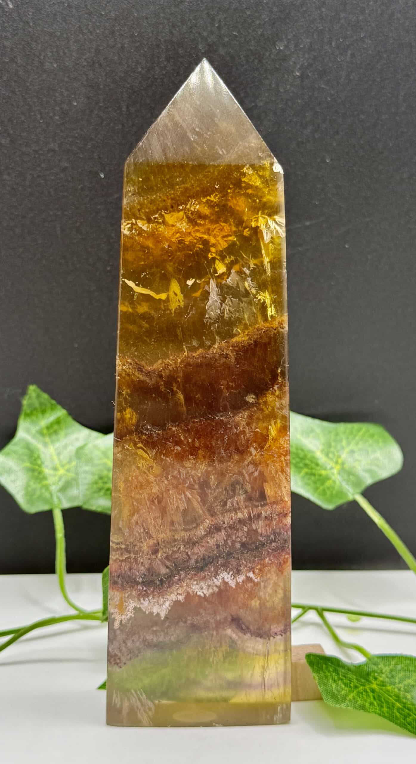 Beautiful polished crystal obelisk with vibrant amber, brown, and gold hues, perfect for energy healing, meditation, and spiritual balance.