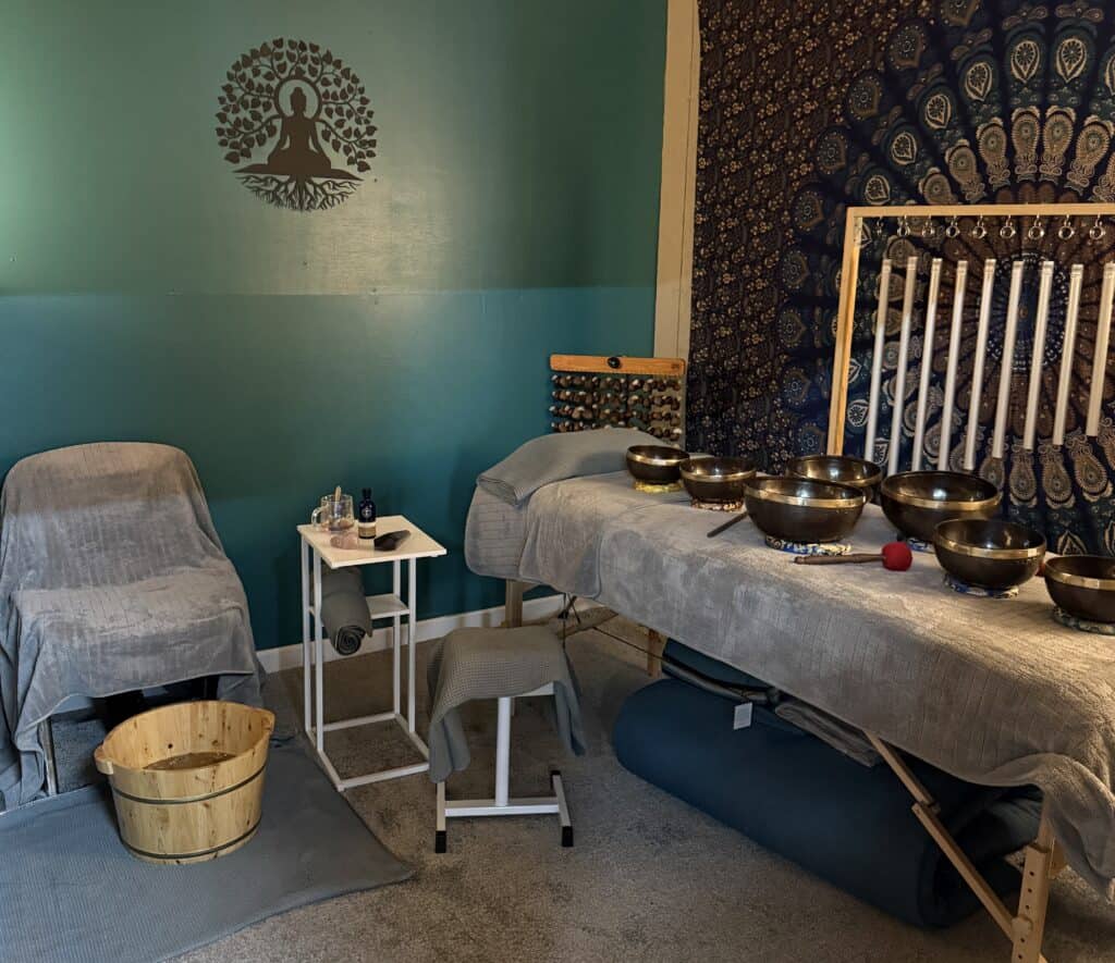 Healing sound therapy room featuring singing bowls, calming decor, and a massage table for relaxation and holistic wellness treatments.