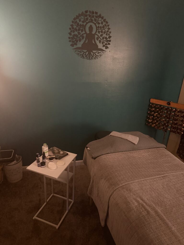Relaxing massage therapy room with a massage bed, essential oils, and calming decor at The Goddess Haven.