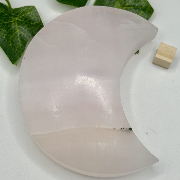 Rose quartz healing crystal moon plate with green ivy leaves and wooden block, ideal for spiritual wellness, meditation, and energy healing. Perfect for holistic decor and crystal healing practices.