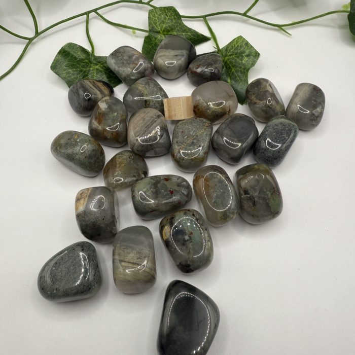 Polished healing stones and crystals displayed on a white surface with greenery, ideal for wellness, meditation, or spiritual practices. Perfect for energy balancing and crystal therapy sessions.